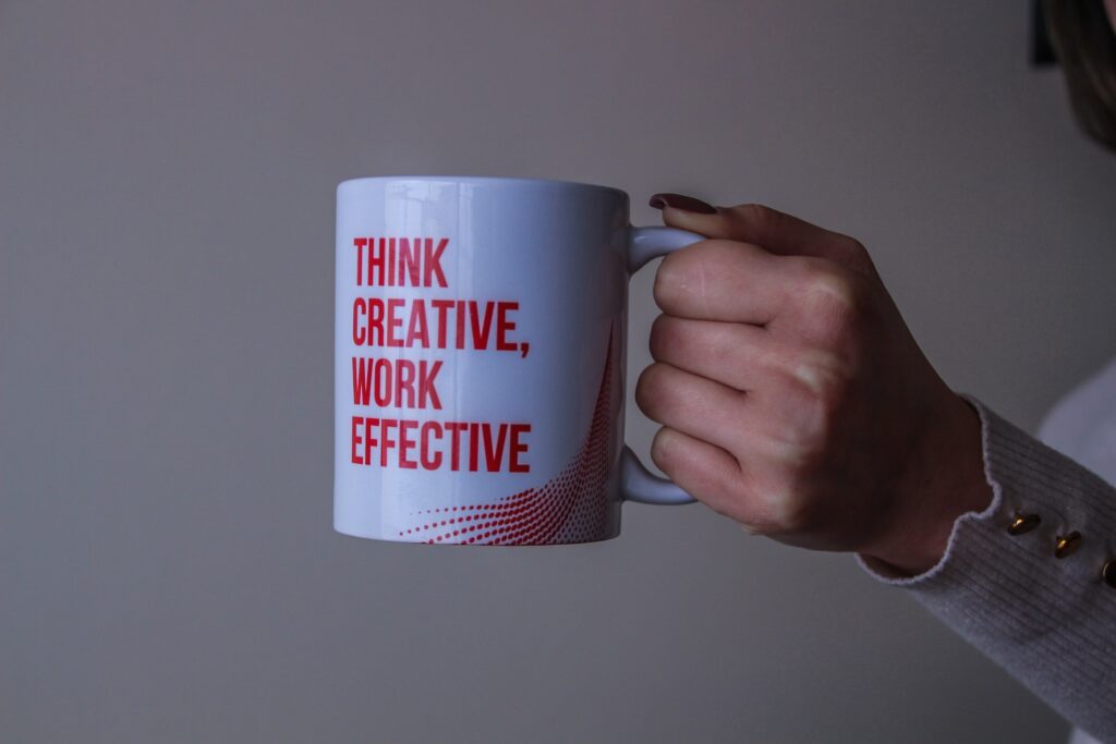 A woman holding a coffee mug “Think creative, work effective”